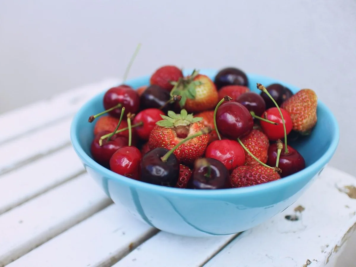 Tigela azul com morangos e cerejas frescas